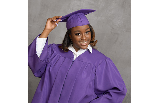 Girl wearing purple graduation gown and hat.