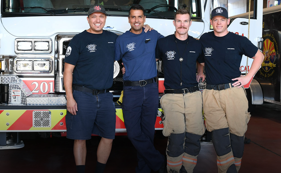 Four Mesa fire fighters standing in front of a fire truck. 