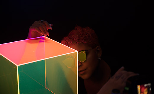 Woman in sunglasses looking at a neon cube installation at Wonder Wonder.