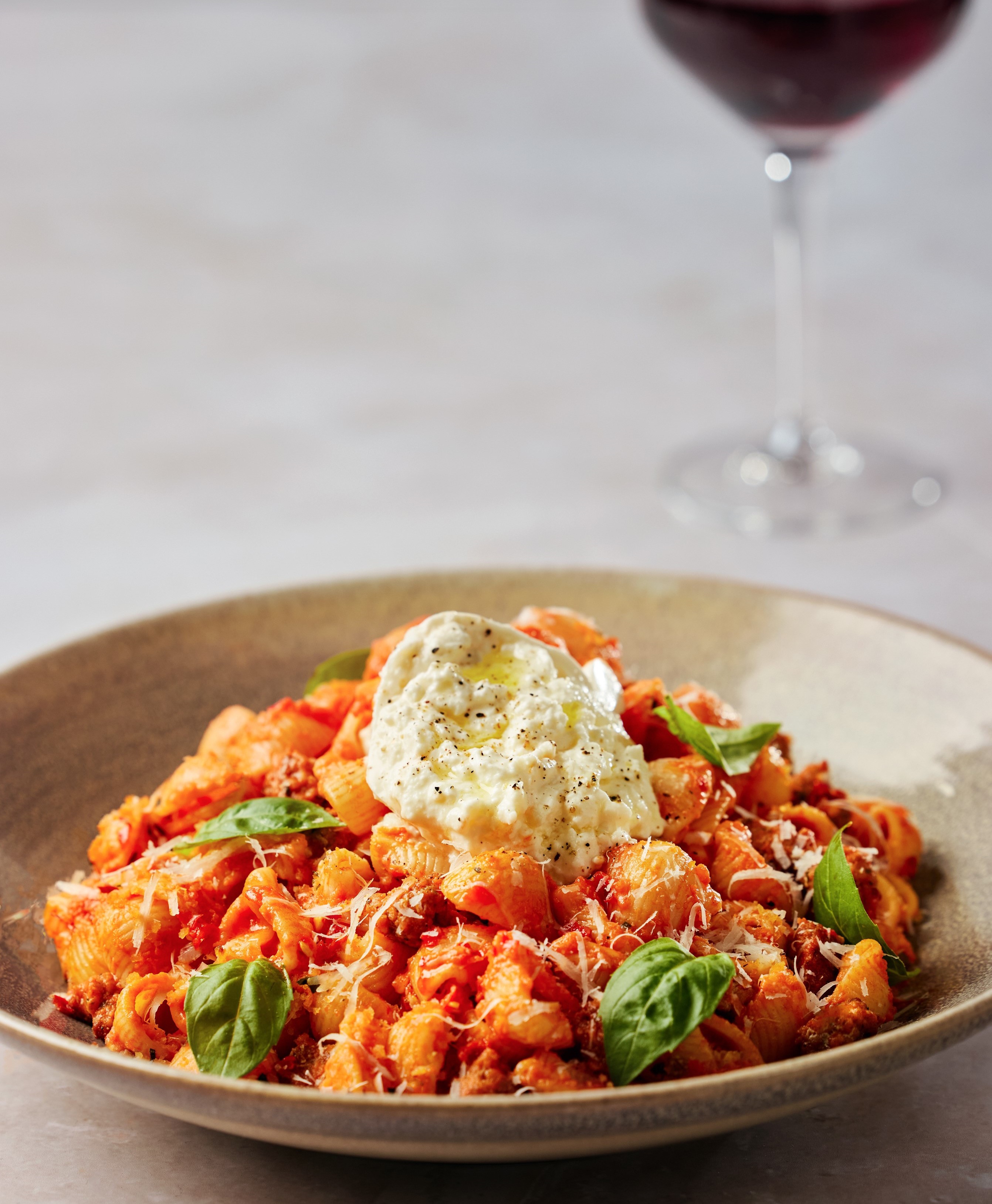 bowl of pasta with fresh basil and a glass of red wine 