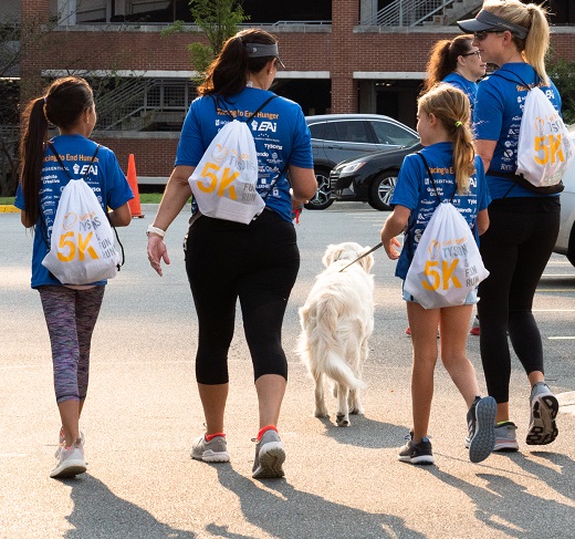 Adults, children and a dog walking with 5K backpacks on