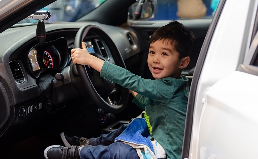 little boy sitting behind the wheel of a law enforcement vehicle 