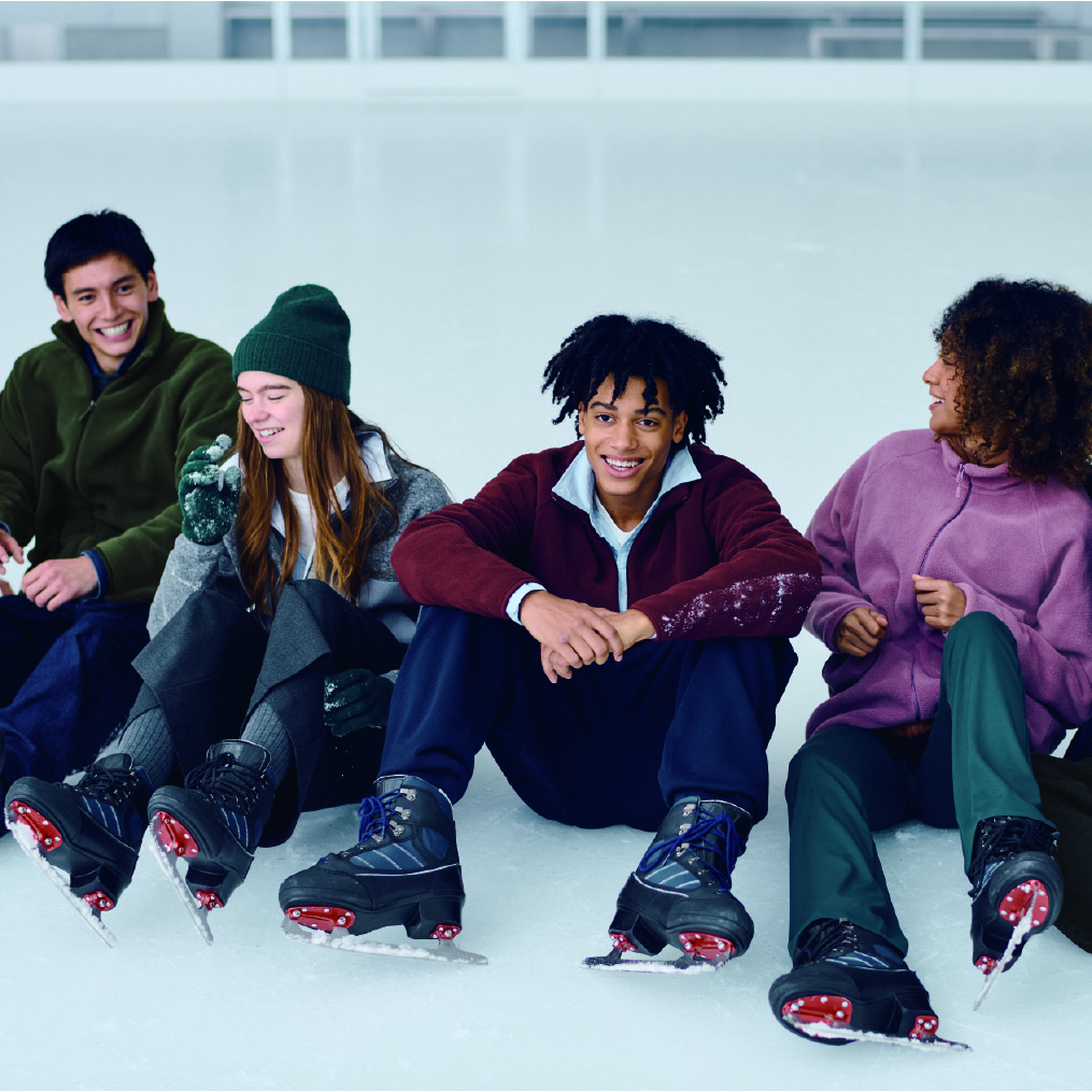 group of kids sitting on an ice rink wearing ice skates 