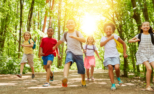 kids with backpacks walking through the woods at summer camp