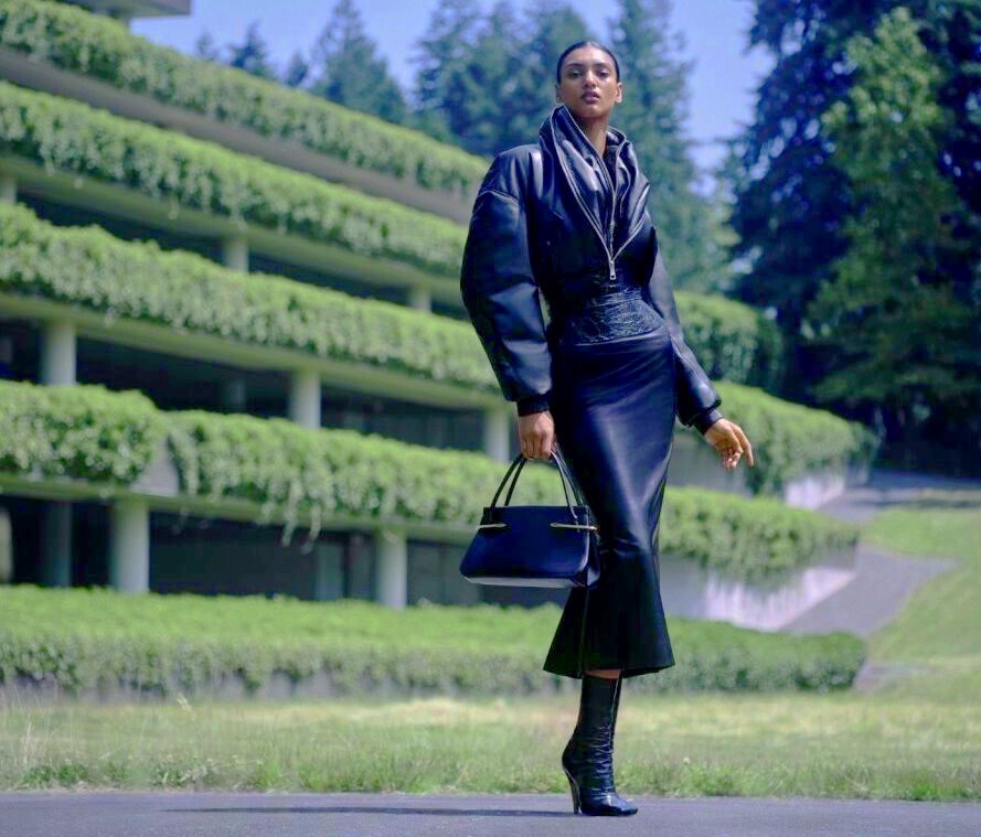 woman in fashionable buff tailored black coat holding a handbag 