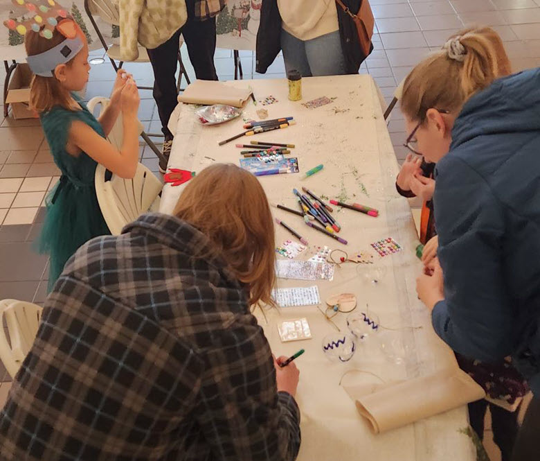 kids and adults decorating homemade ornaments.