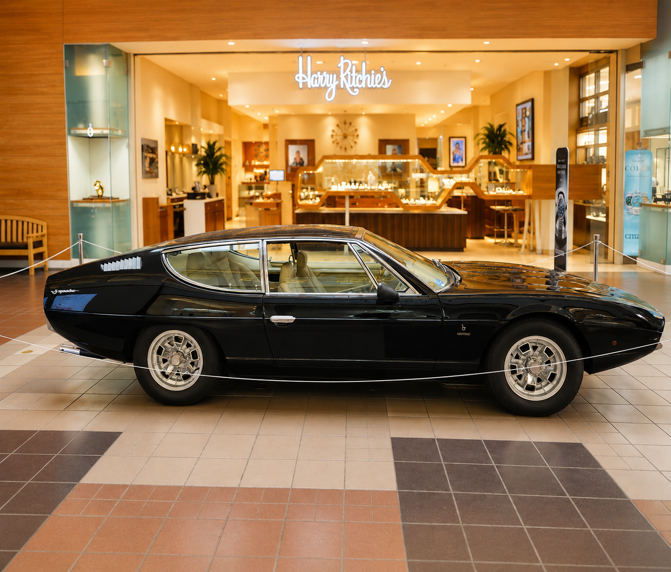 A black vintage car on display inside of a mall.