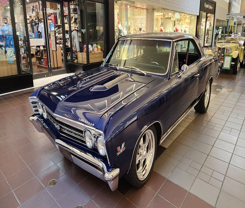 A blue vintage car on display inside of a mall.