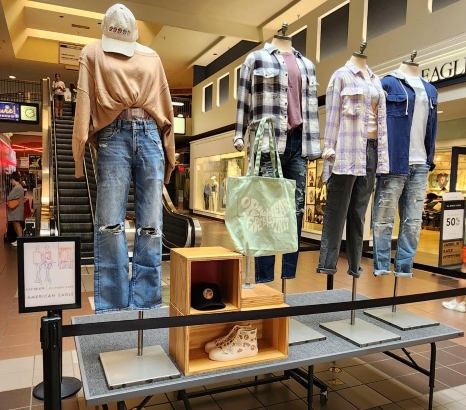 Four mannequins dressed up in long sleeved shirts and jeans, on display, inside of the mall.