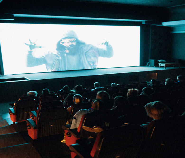A group of people watching a scary movie inside of a movie theatre. 