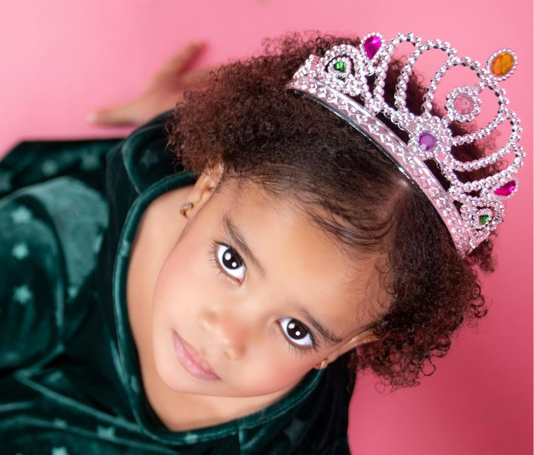 A little girl dressed up in a princess outfit and wearing a tiara on her head.
