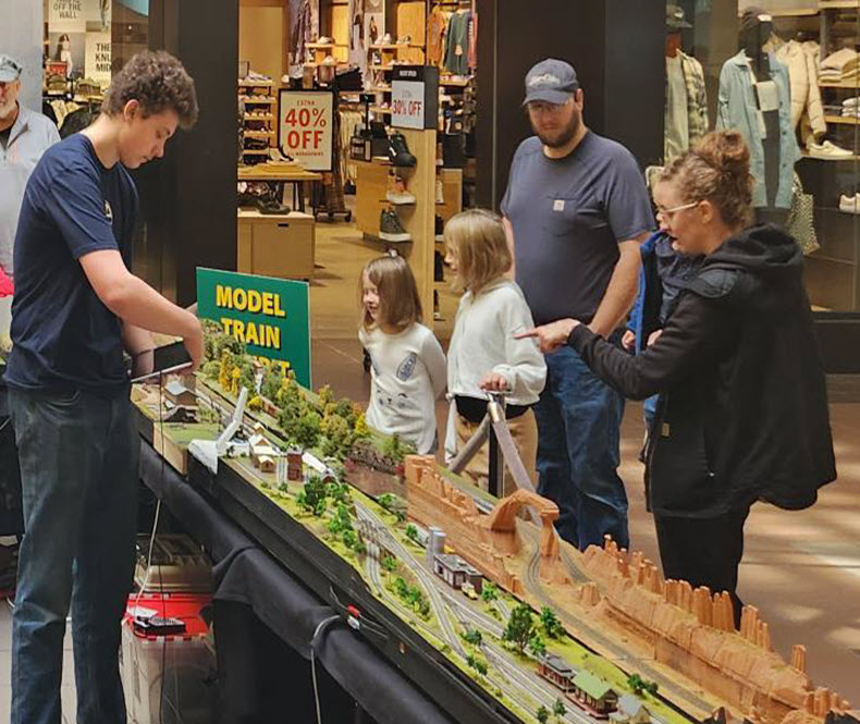 A family looking at a model train track.