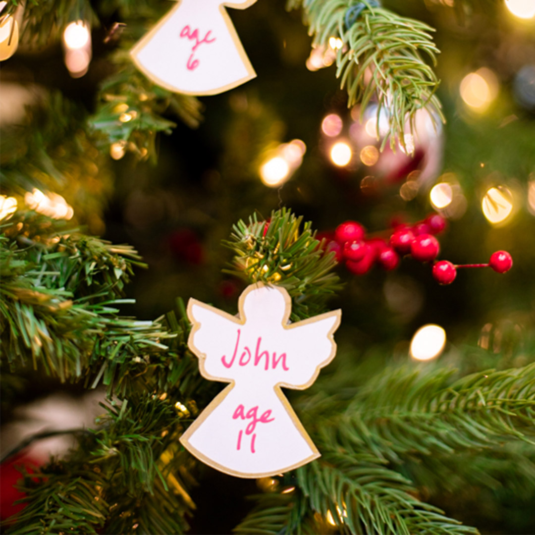 angel ornaments with children's names and ages listed hanging on a tree.