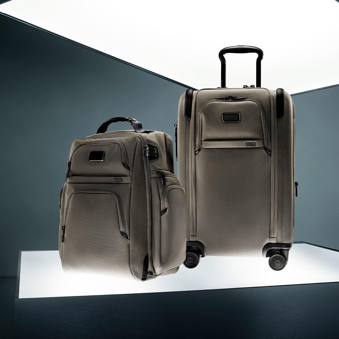 A TUMI roller bag and duffel bag on a lit podium 