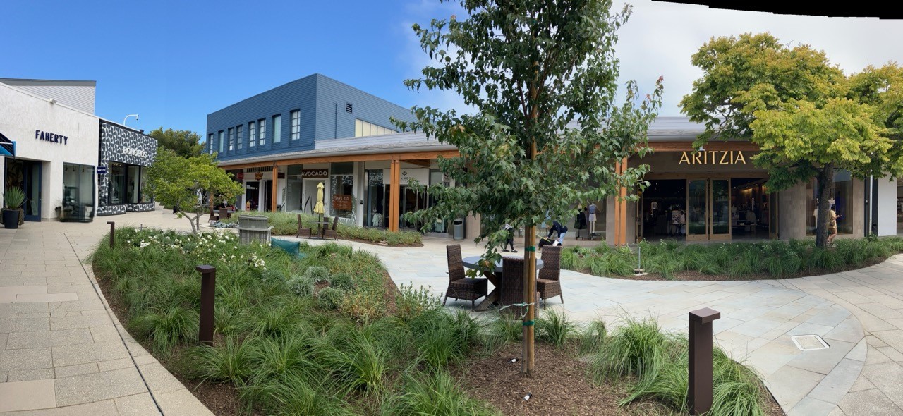 Landscaping and seating of an outdoor Center with an Aritzia store in the background. 