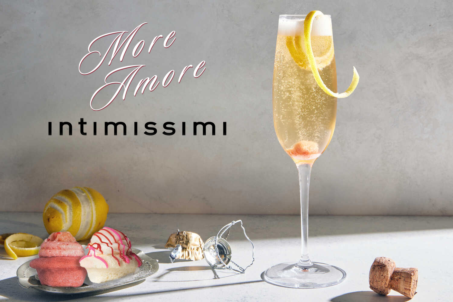 A glass of champagne and a plate of chocolate truffles against a backdrop that says More Amore Intimissimi