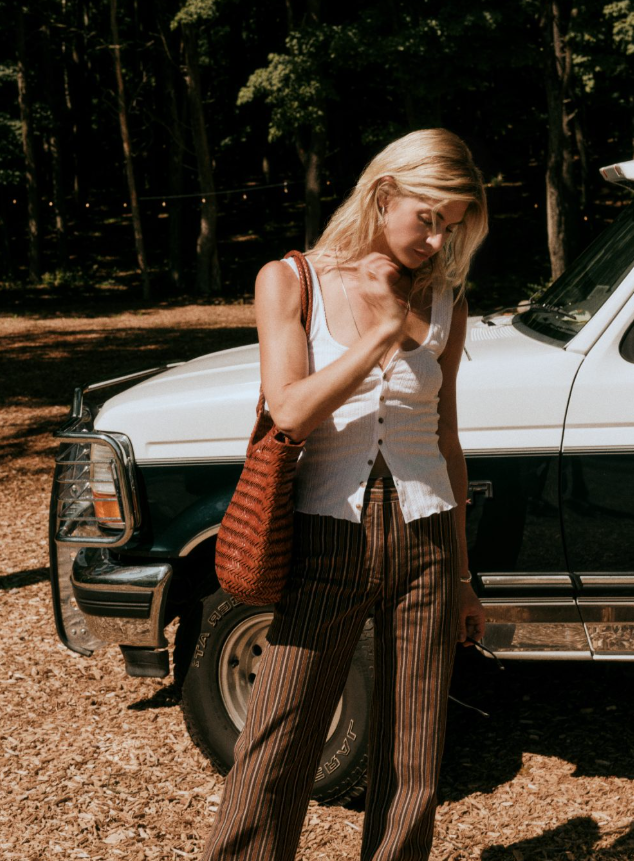  A woman in brown pants and a white vest standing in front of a truck