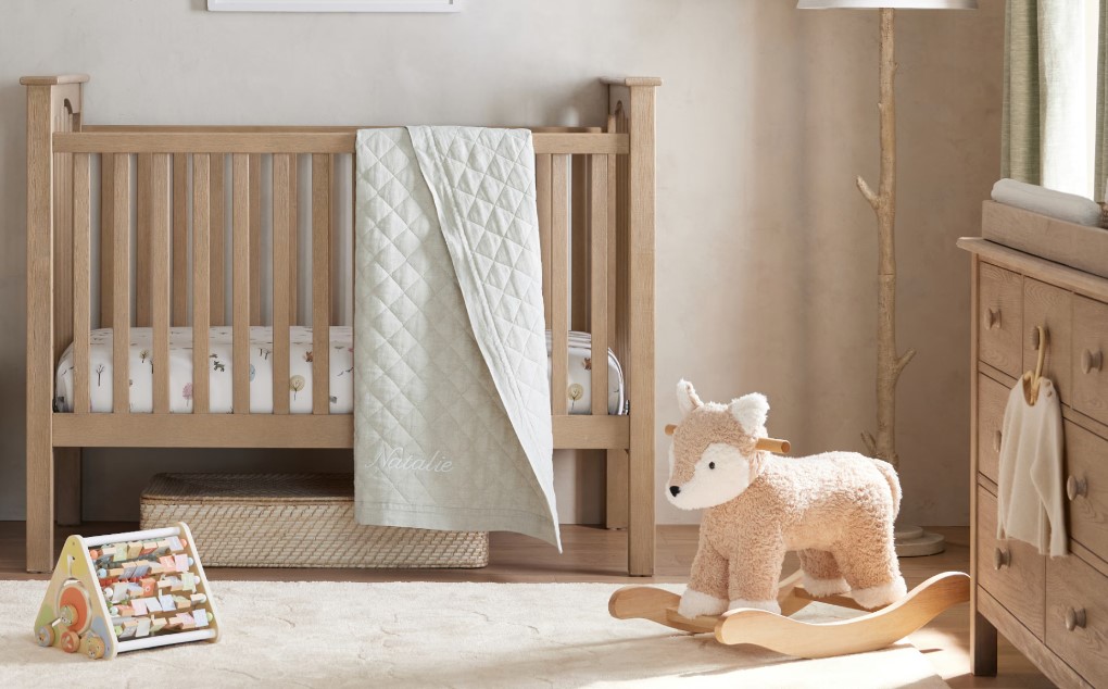 A nursery with a crib, fox rocking horse and changing table 