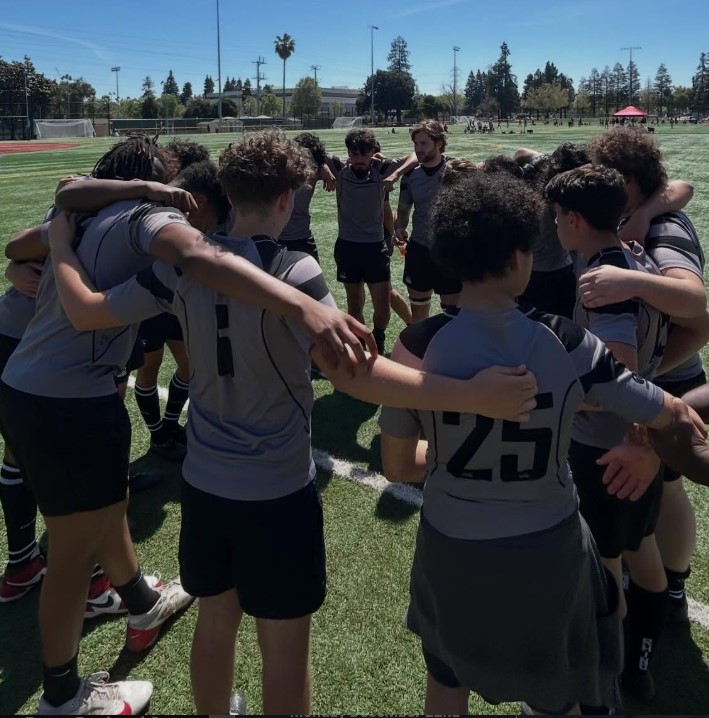 A group of young teen rugby players in a circle on a field