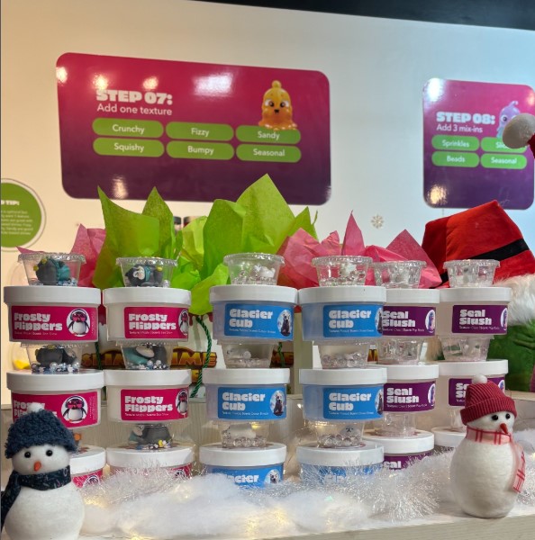 Containers of slime on a counter with some snowman plushes in the Slime Kitchen 
