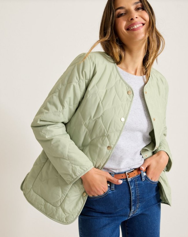 A woman in blue jeans wearing a green quilted jacket from Tommy Bahama