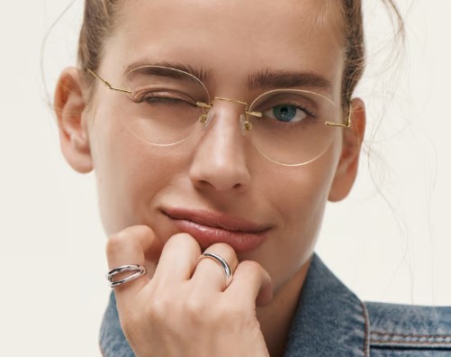 A blond woman is winking wearing rimless frames from Warby Parker