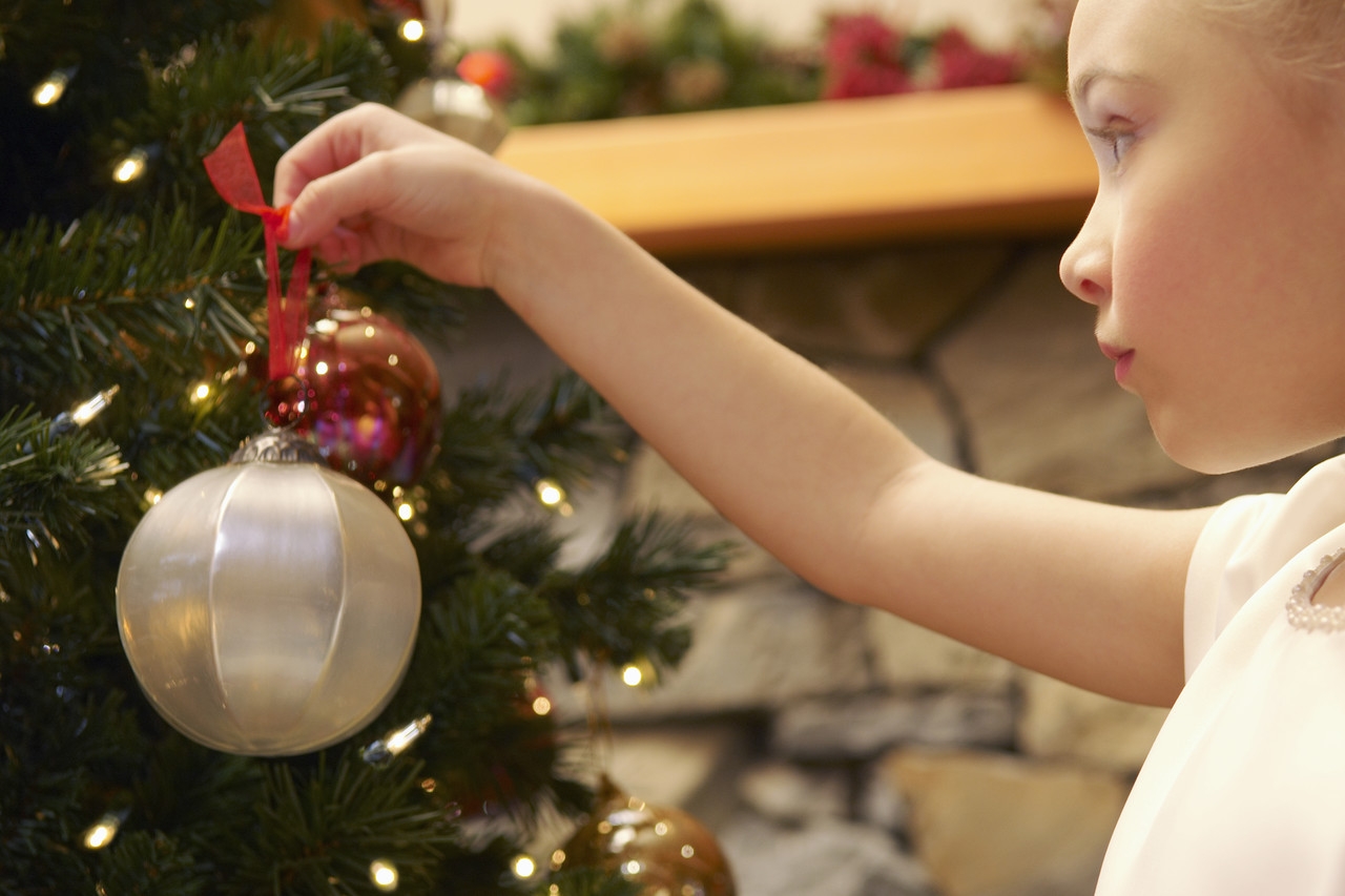 child putting  ornament on a tree