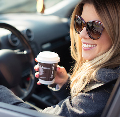 woman with coffee and sunglasses sitting in a car