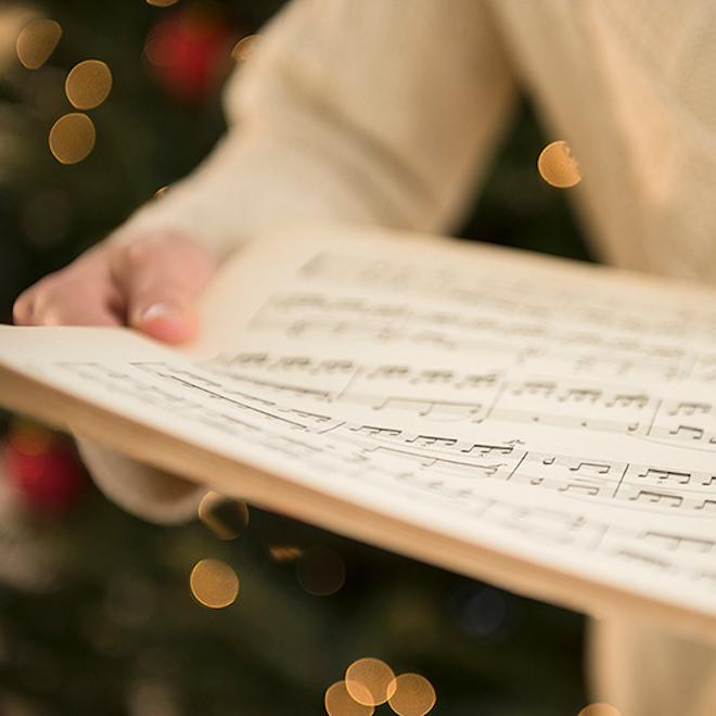 a person holding sheet music for holiday choir