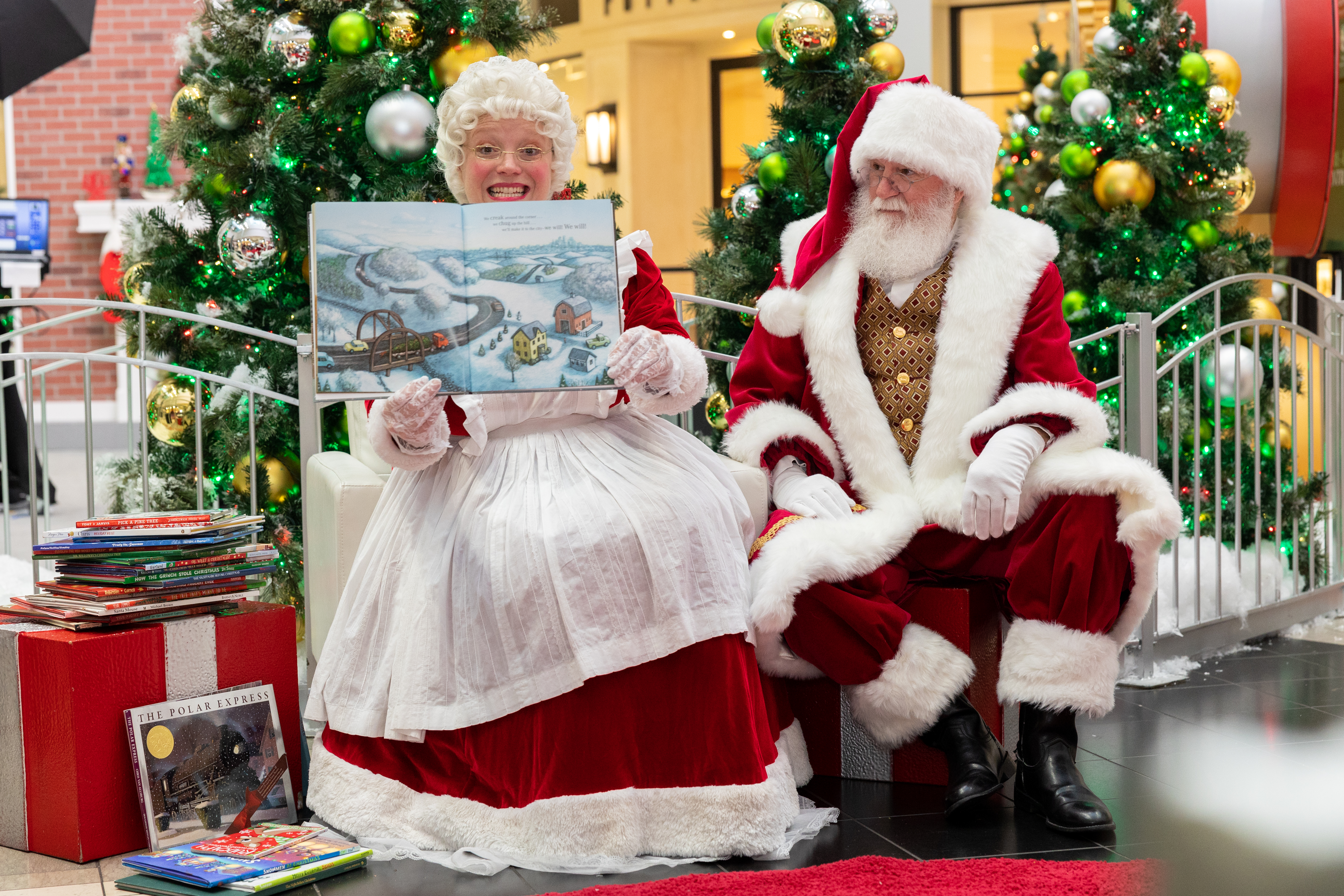 Mrs. Claus reading a Christmas book with Santa Claus sitting next to her