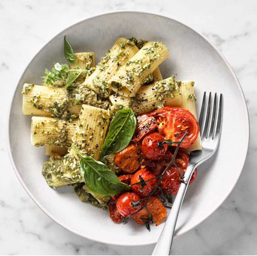 a plate of pasta and roasted tomatoes on a marble counter