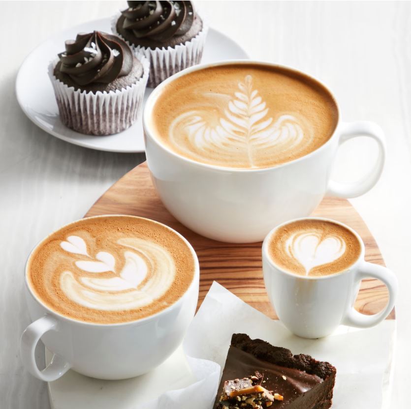 white coffee cups filled with cappuccinos and lattes
