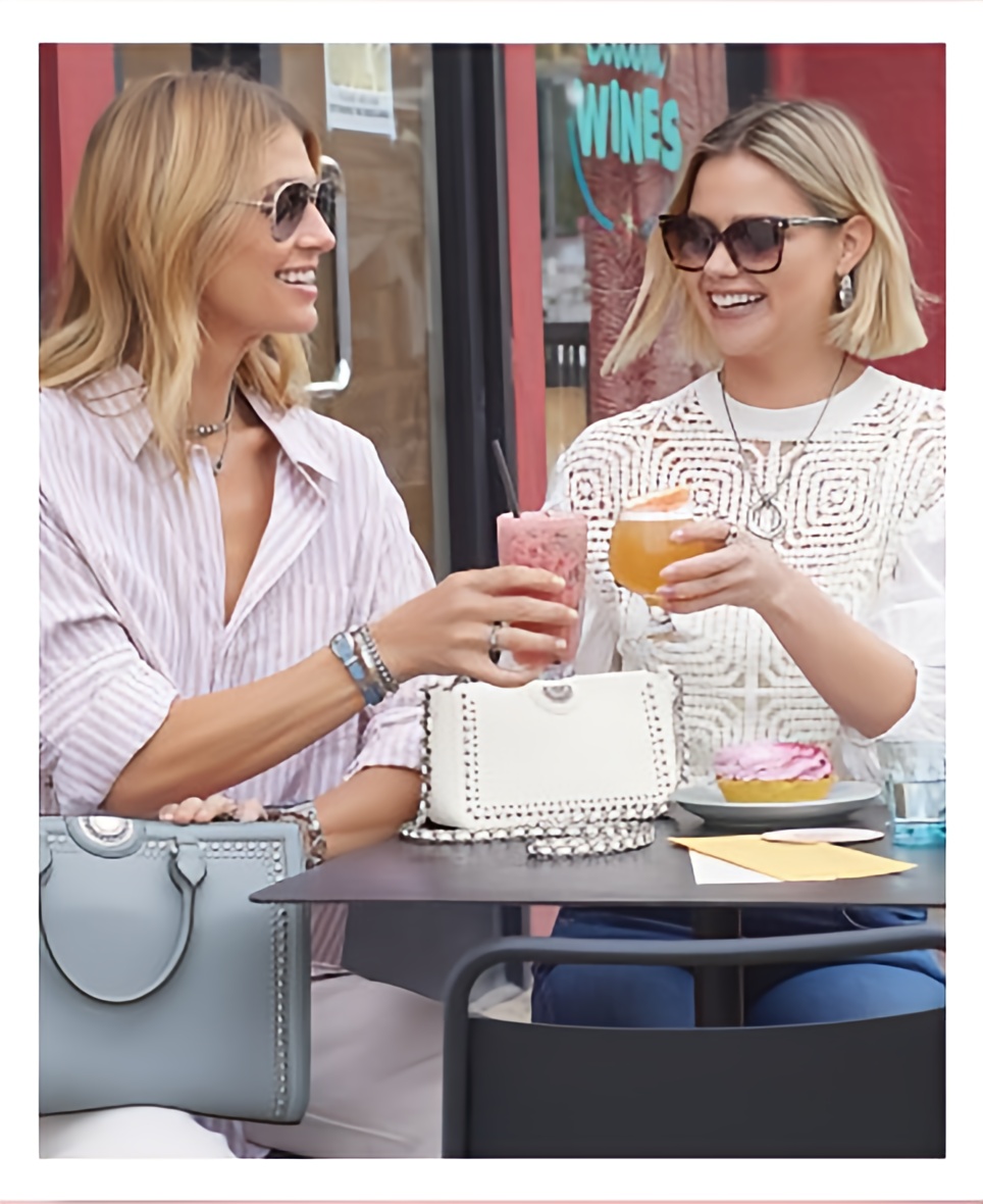 two women at an outdoor cafe toasting champagne