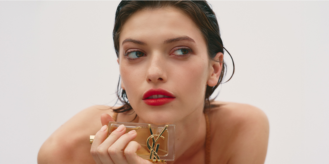 A woman holding a bottle of fragrance