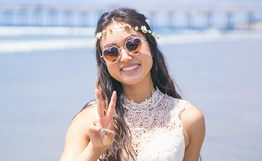 girl smiling wearing shades with beach boardwalk back drop