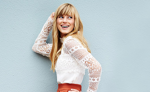 A model wearing a lacy blouse and posting