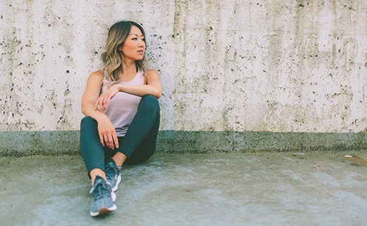 A woman in athletic wear leaning against a wall. 