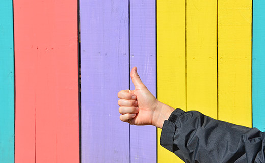 thumbs up in front of multi color fence