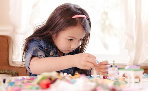 little girl working on craft at table. 
