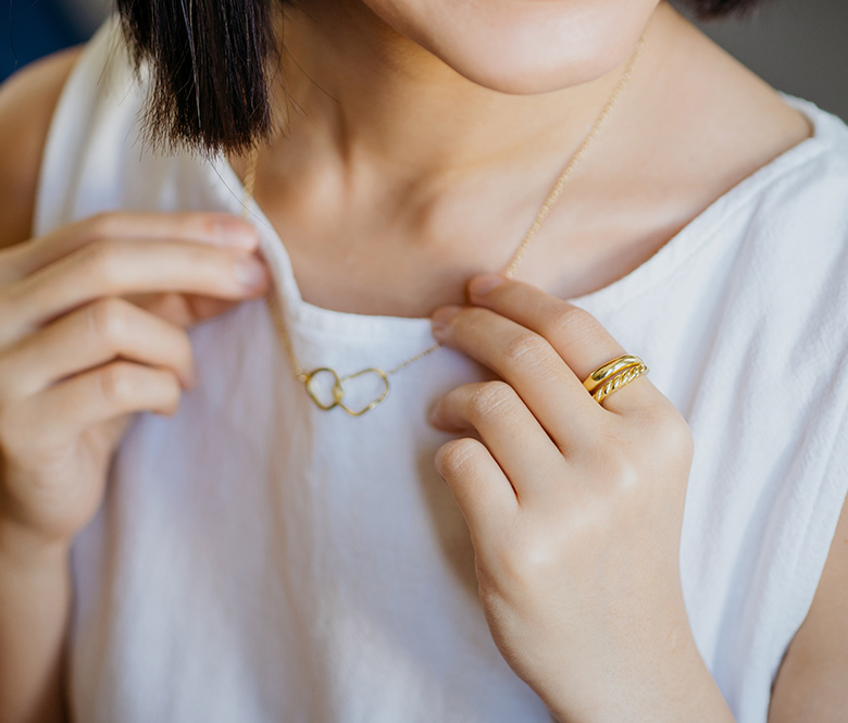 girl in white tee shirt wearing a gold necklace and gold ring