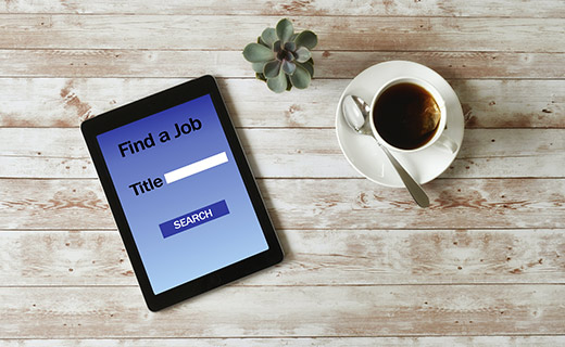 Tablet with "Find a job" image on coffee table with coffee cup