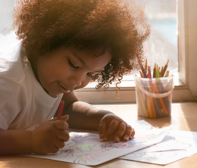Little girl drawing pictures with crayons