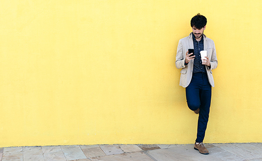 Man posing against wall with coffee in hand 