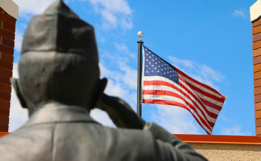 A statue of a veteran saluting an American flag for Memorial Day hours