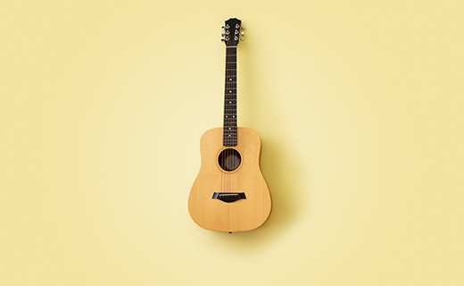 Wood acoustic guitar on a yellow background.