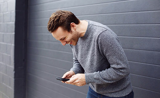 man smiling looking down at cell phone