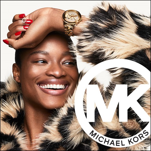 Michael Kors logo. Woman wearing tan and black fur like coat, wearing gold MK watch,