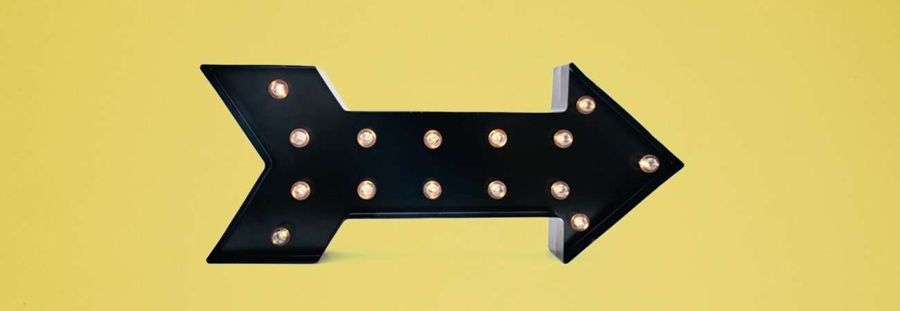 Illuminated black arrow sign with yellow background