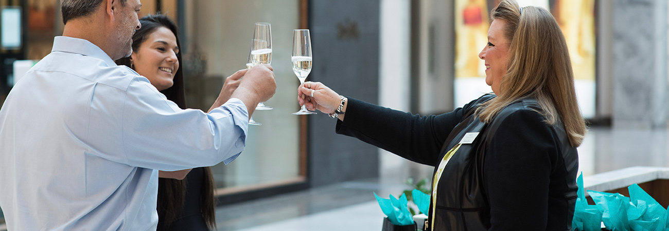 The concierge raising a champagne toast with two shoppers at Scottsdale Fashion Square