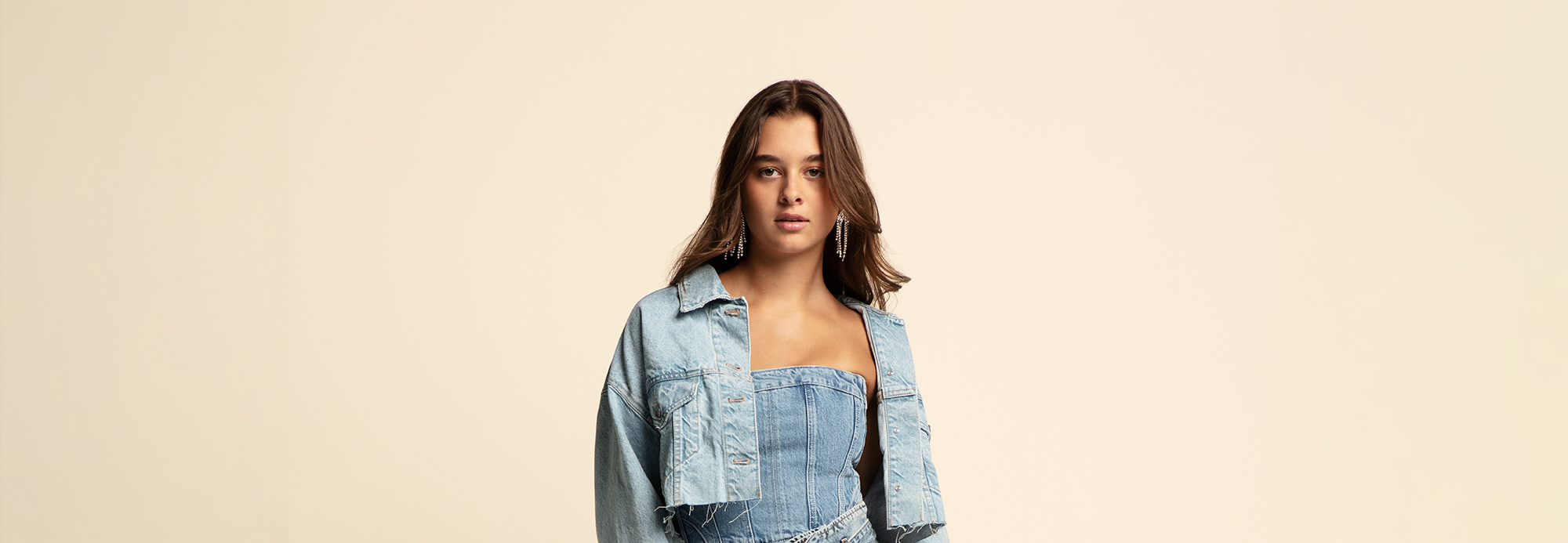 A young woman wearing a denim cropped jacket and denim sleeveless jumpsuit